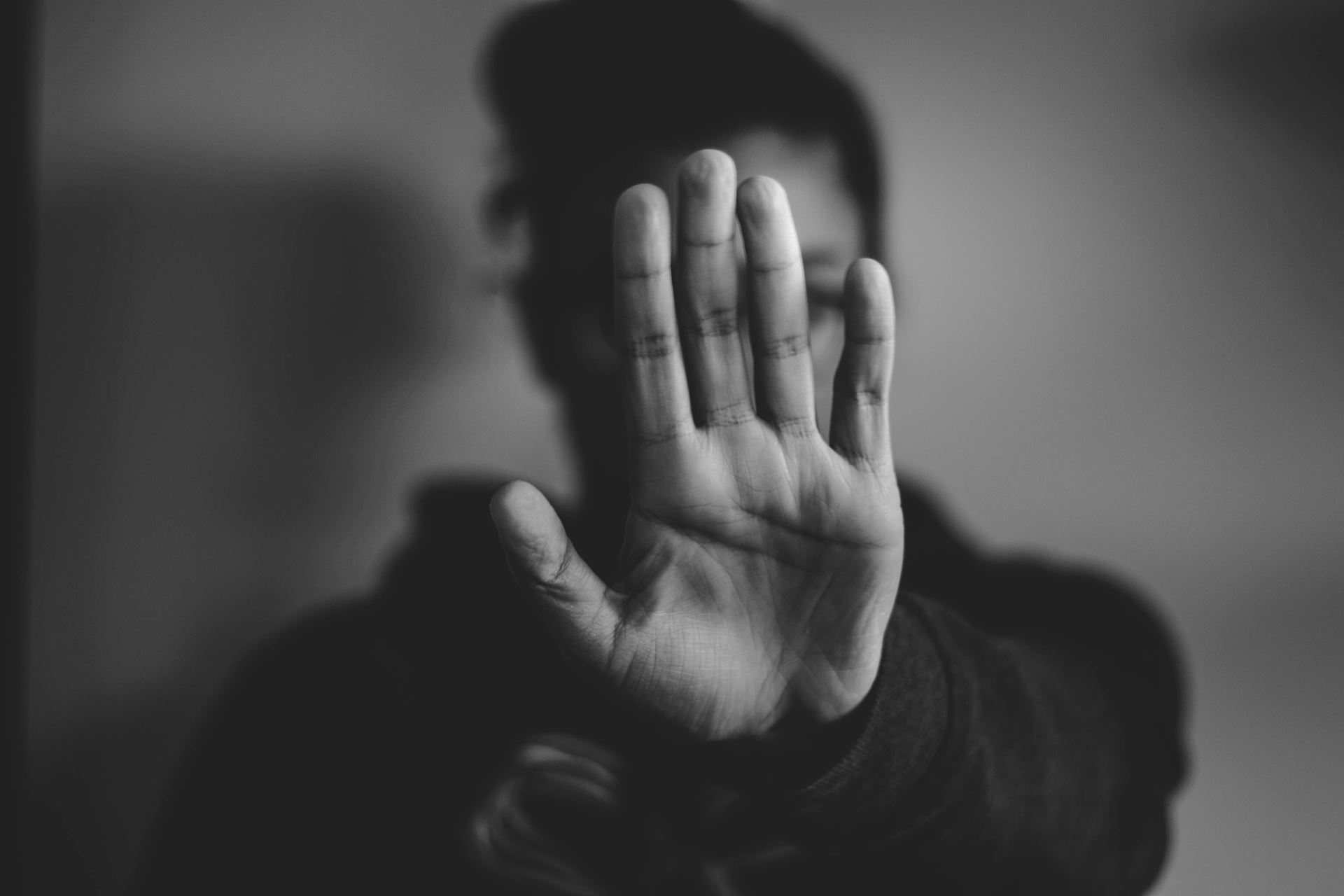 Black and white photograph of a hand held in the stop position